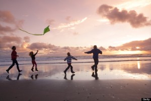 Family on beach at sunset with kite
