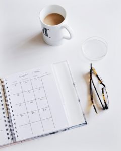 Coffee cup, calendar, and glasses on desk
