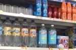 Various bottles containing different kinds of water on a shelf in the grocery store.