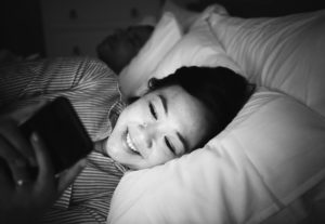 Asian women in bed looking at phone