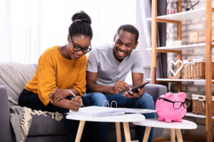 Young Couple Sitting On Sofa Calculating Invoice