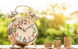 Clock and stacks of coins with plants growing out of them